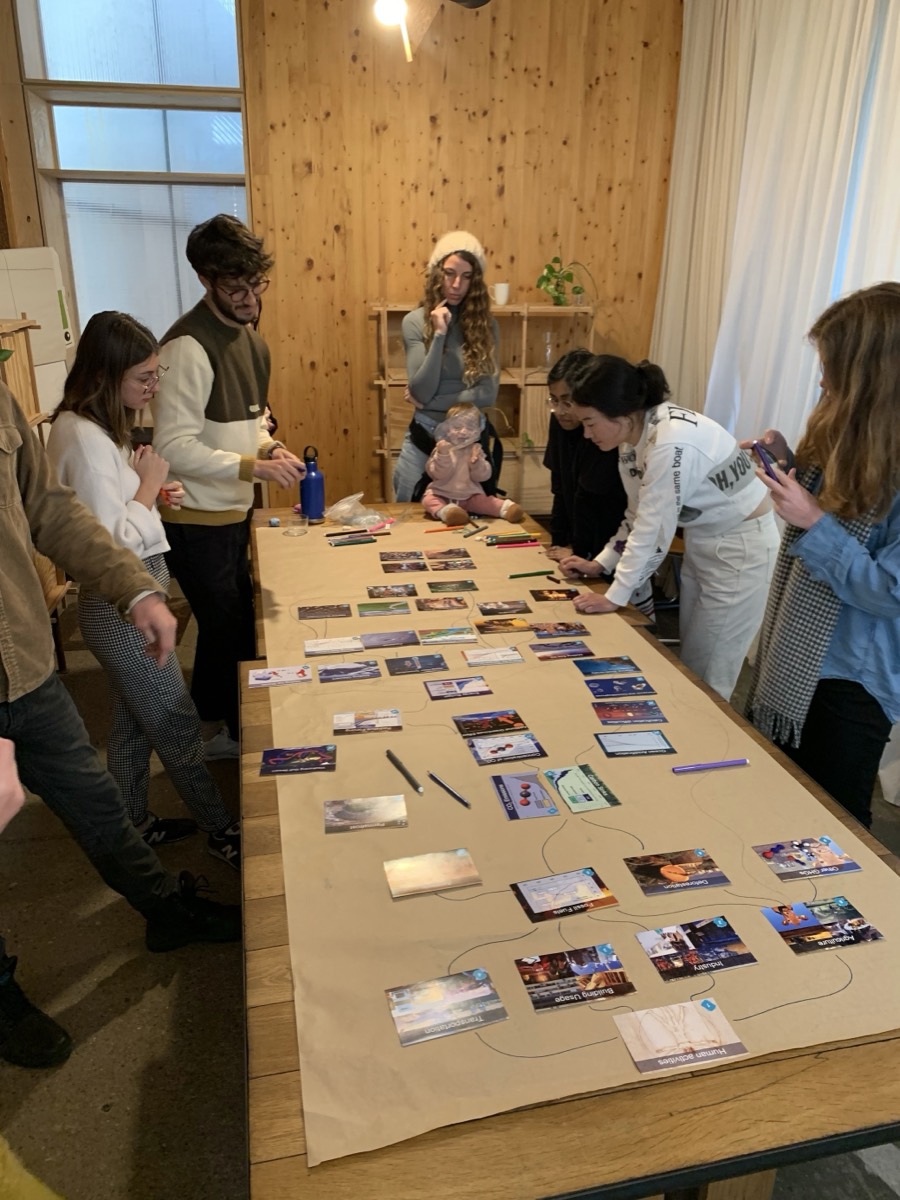 Un equipo reunido alrededor de una mesa construyendo un mural de cartas